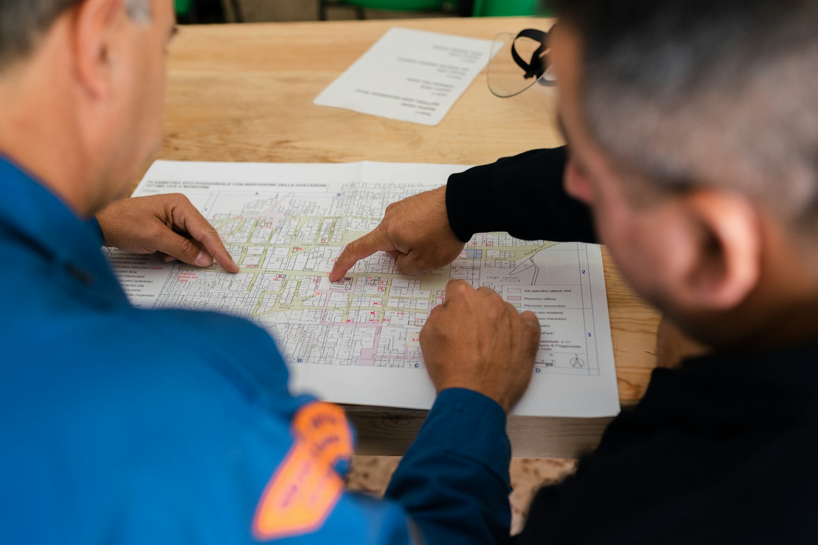 Deux techniciens en tenue de travail échangent sur un plan en atelier