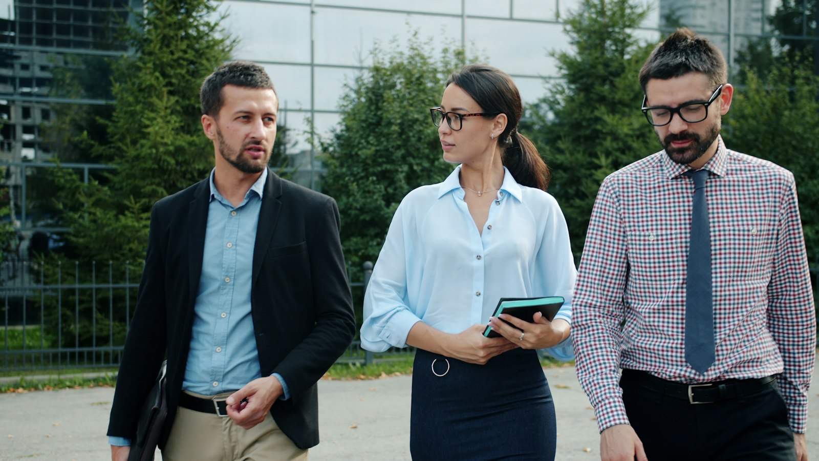 Trois dirigeants marchent devant un immeuble de bureaux